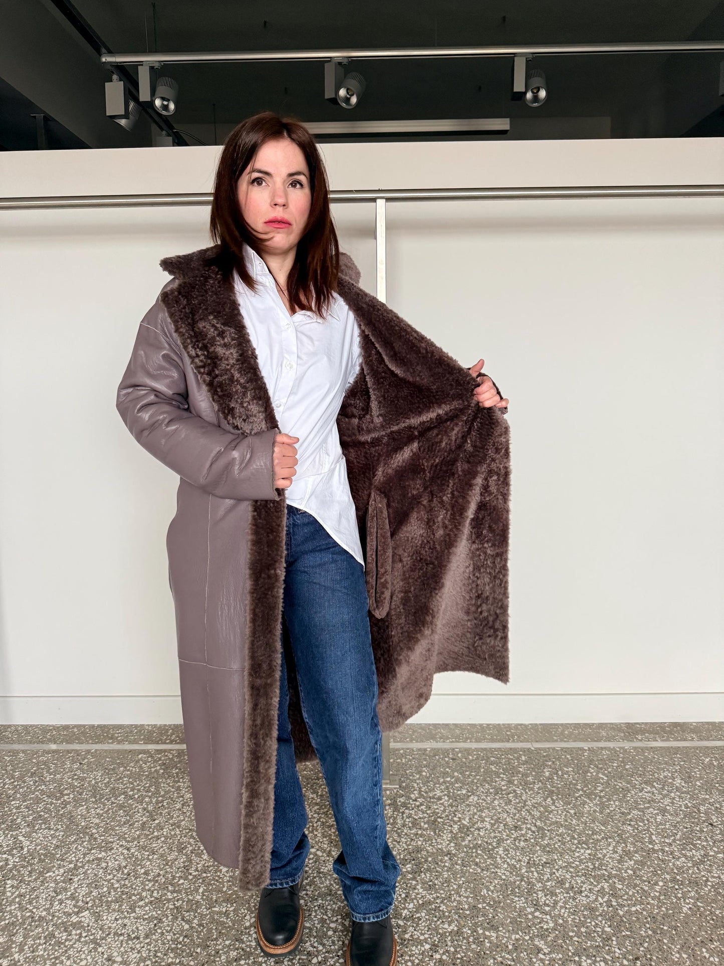 Reversible grayish merino shearling and leather coat: Super warm and soft brown Sheepskin stroller with tie belt closure.