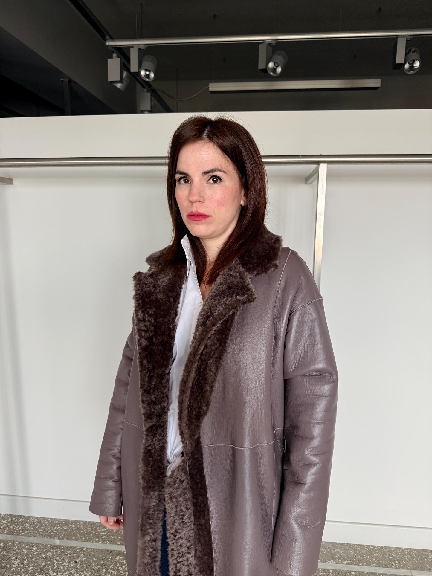 Reversible grayish merino shearling and leather coat: Super warm and soft brown Sheepskin stroller with tie belt closure.