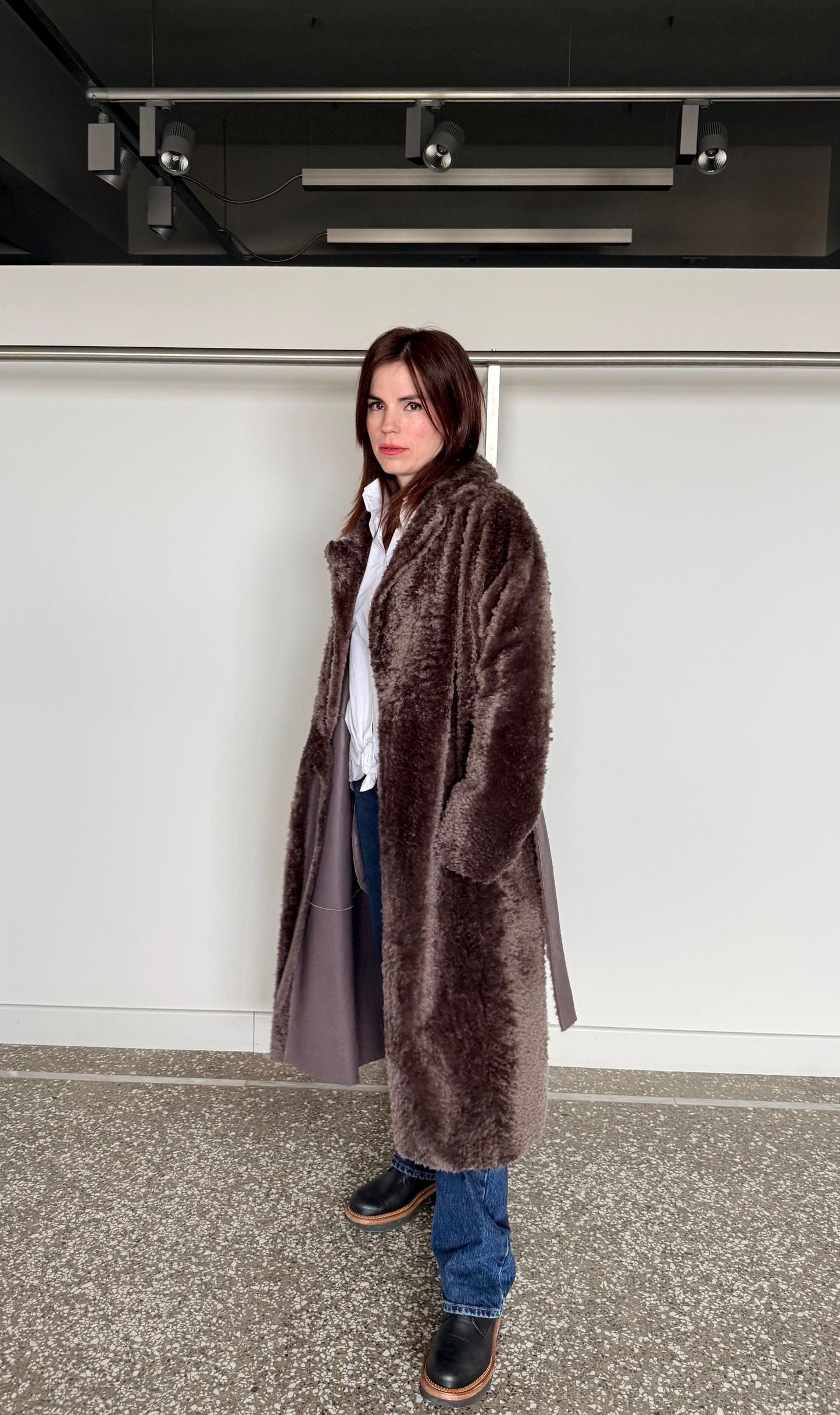 Reversible grayish merino shearling and leather coat: Super warm and soft brown Sheepskin stroller with tie belt closure.
